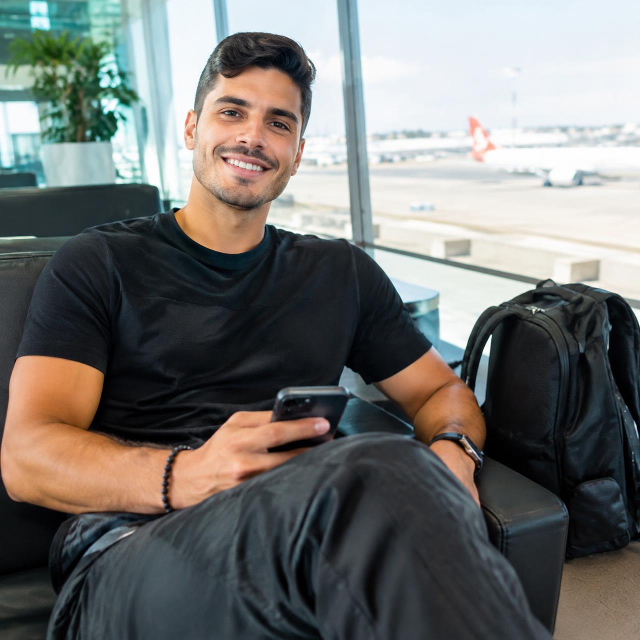 Viajante sorrindo com o celular em uma sala de embarque do aeroporto